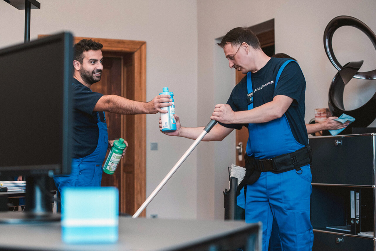 3 Mitarbeiter reinigen gemeinsam ein Büroraum. Im Team geht die Arbeit schnell und effizient voran.